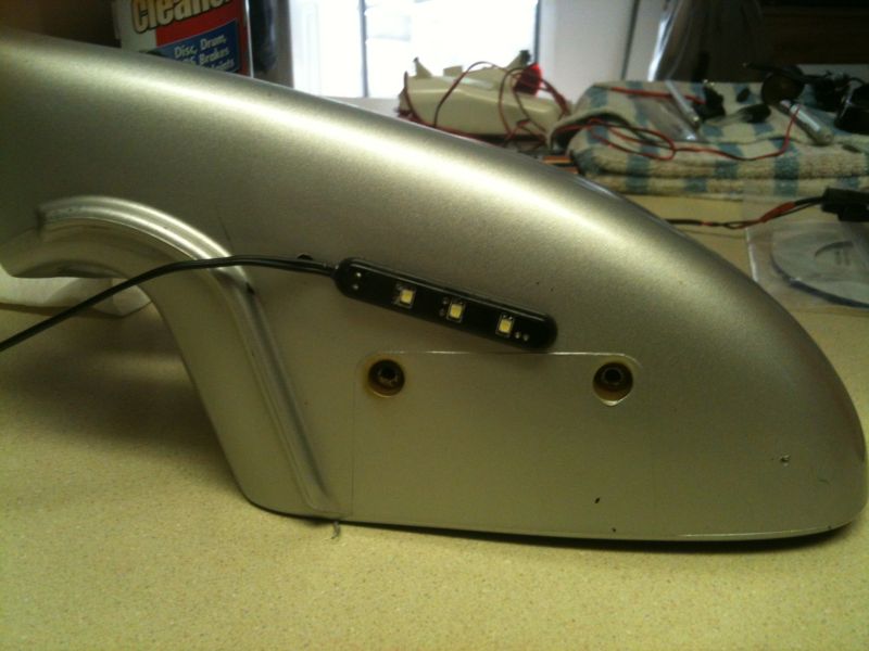 Silver fender with LED light strip and black wire.