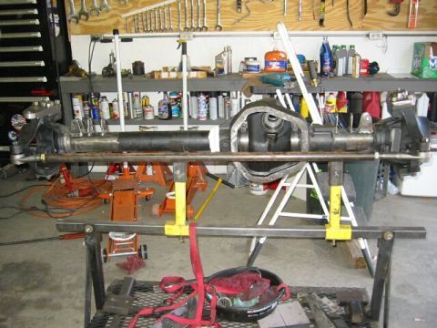 1994 Ford Bronco - Front axle assembly for a 1994 Ford Bronco, supported by jack stands in a workshop.