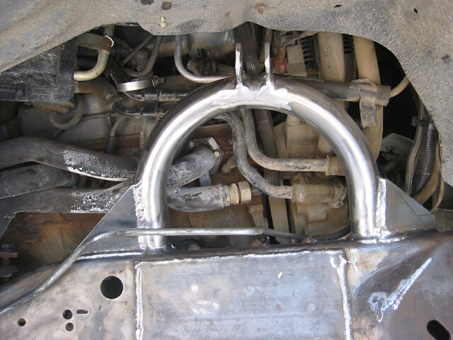 Freshly welded bare-metal tubular hoop bracket on a truck front frame crossmember