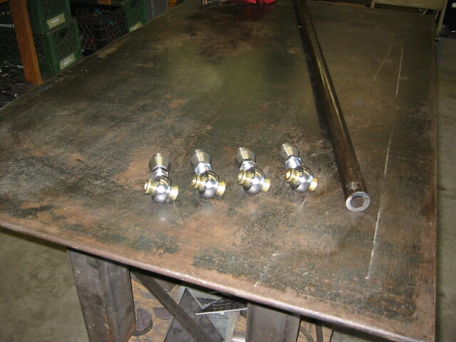 Four heim-joint rod ends and a steel tube on a workbench