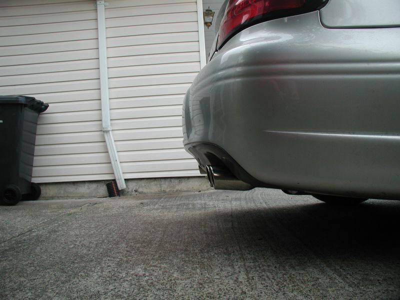 Silver sedan rear bumper and chrome exhaust pipe, low angle