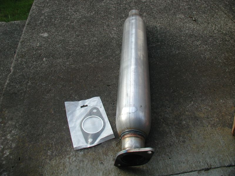 Silver exhaust muffler and gasket on concrete.