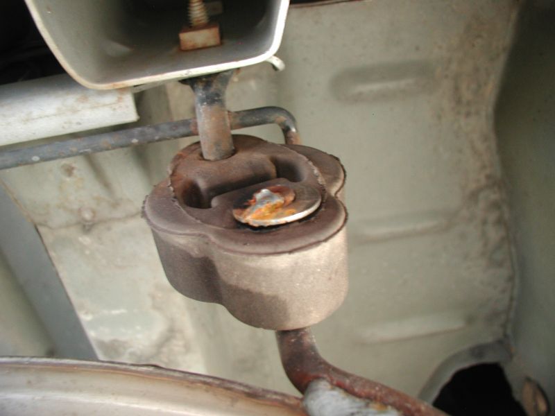 Rusted exhaust hanger bracket on a vehicle undercarriage