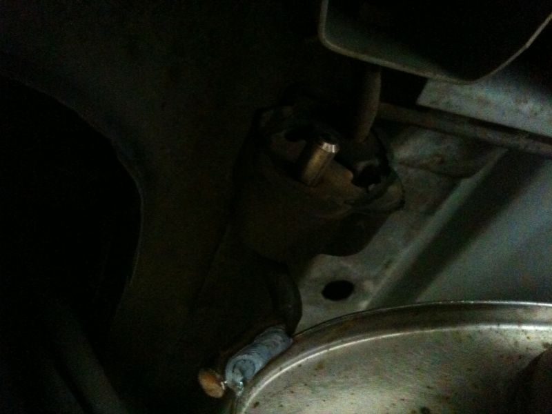 Underside of a car showing a broken exhaust hanger and part of the muffler.