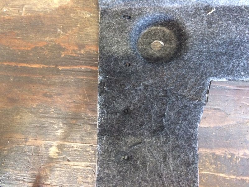 Dark gray carpeted panel with clips on a wooden surface.