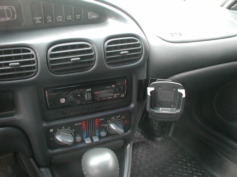 Car dashboard interior with JVC stereo, climate controls, and phone holder.