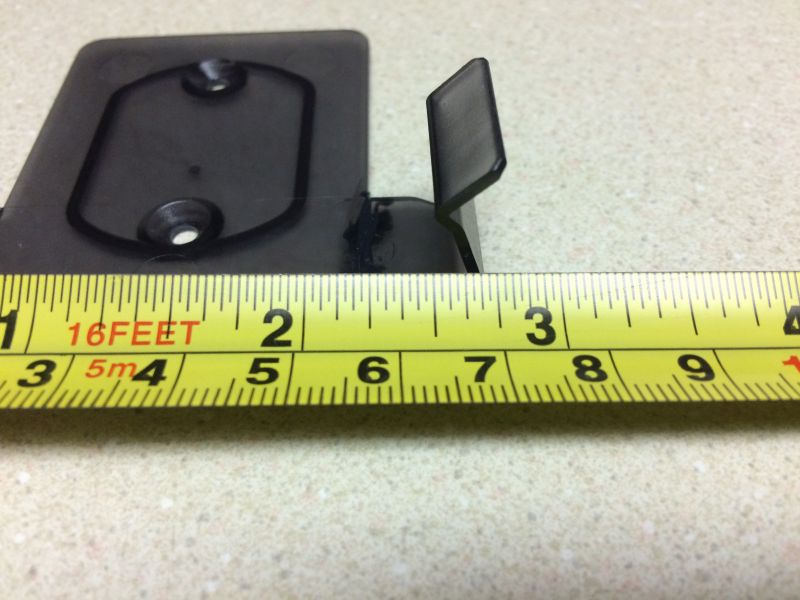 Black plastic part being measured by a yellow tape measure.
