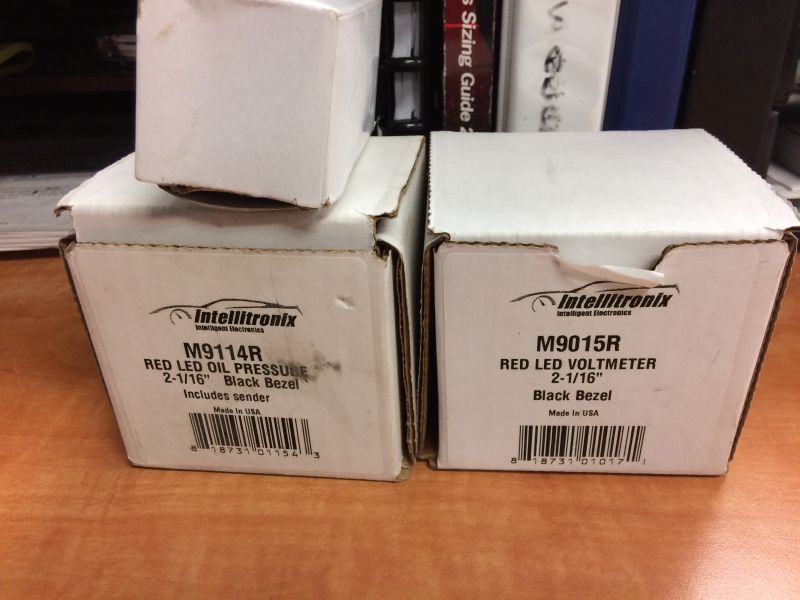 Two boxes for Intellitronix gauges: M9114R Oil Pressure and M9015R Voltmeter.