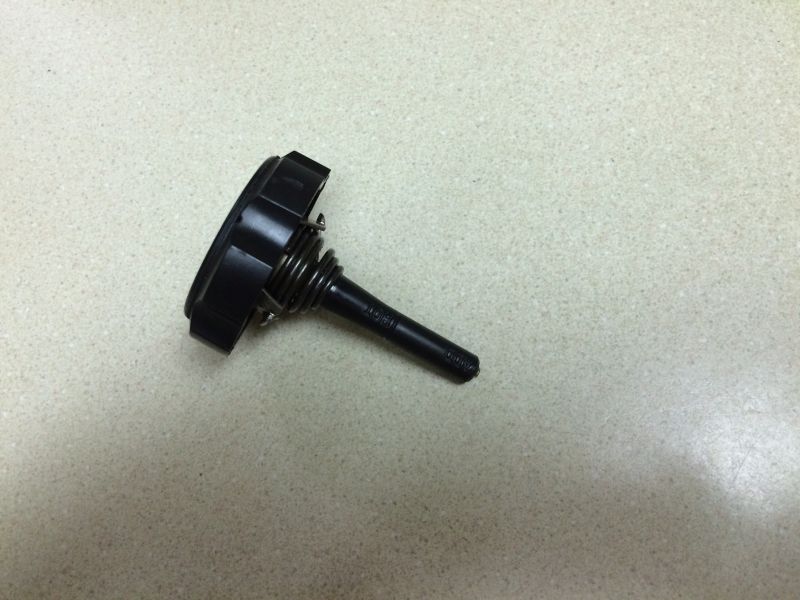 Black plastic cap with spring-loaded plunger on speckled surface
