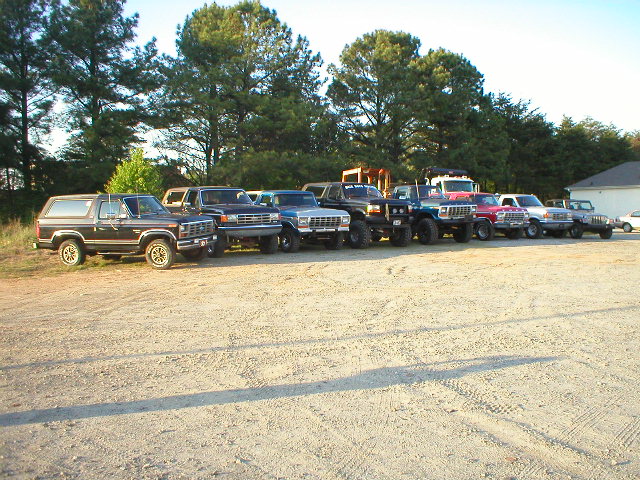 1989 Ford Bronco and other SUVs parked in a line on a gravel lot