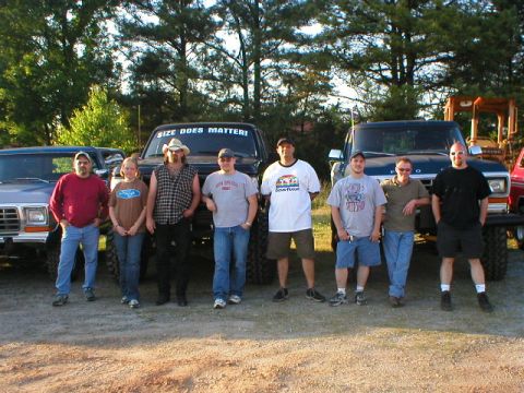 1989 Ford Bronco - Several people stand in front of lifted Ford Broncos and a tractor.