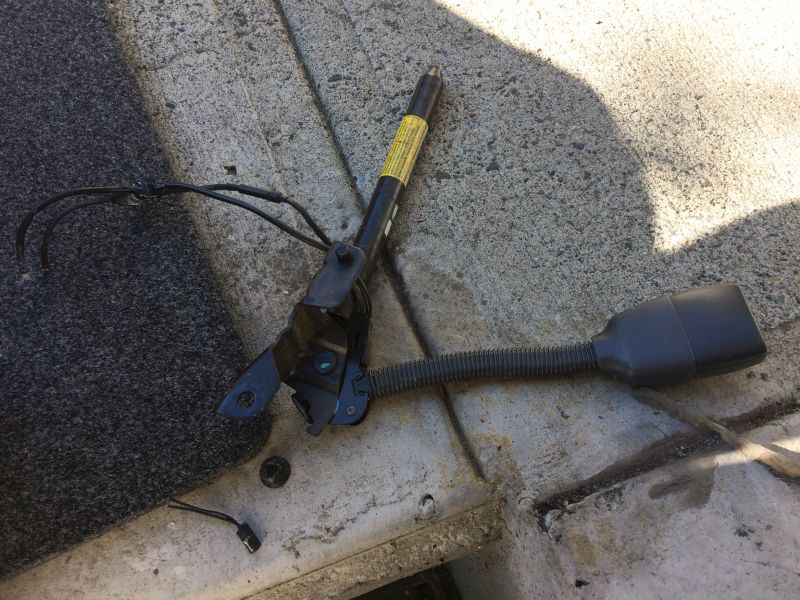 Detached seatbelt buckle assembly with wiring on concrete
