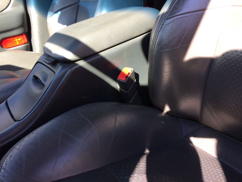Car interior with leather seats, center console, and a red seatbelt buckle.