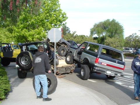 1989 Ford Bronco - Several modified off-road vehicles, including a 1989 Ford Bronco, are loaded onto a trailer.