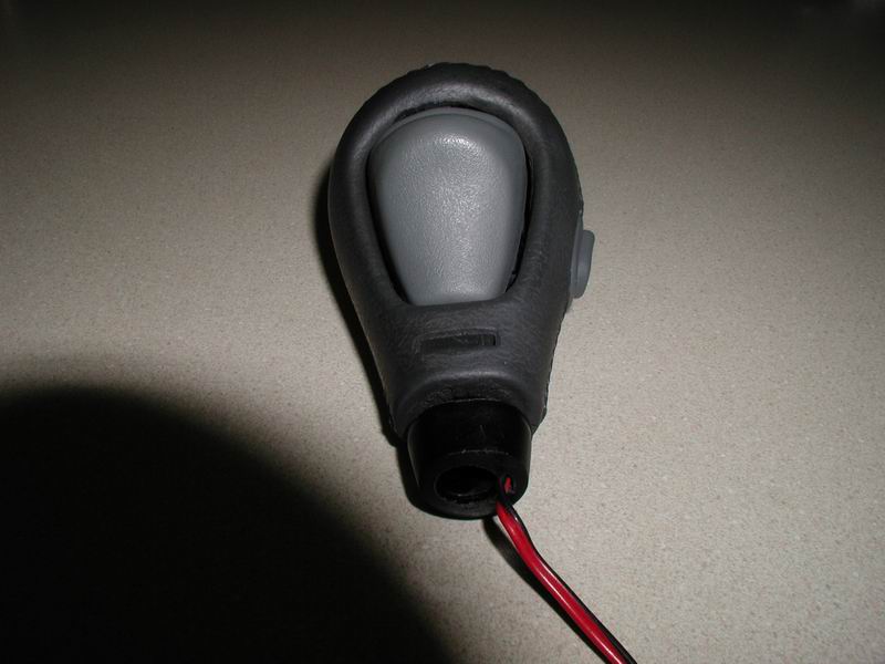 Gray and black gear shift knob with wires protruding from the base.