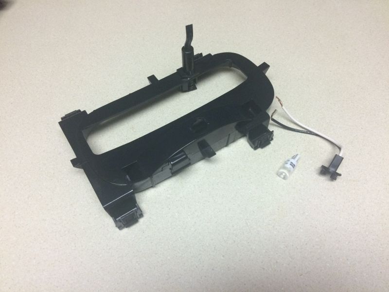 Black plastic automotive trim piece with wiring on countertop