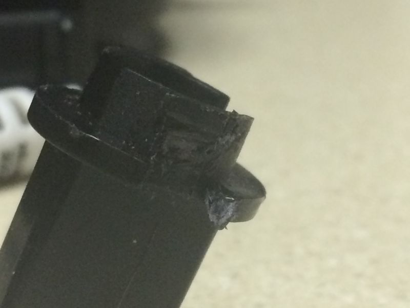 Damaged black plastic automotive connector or clip with broken and melted edges.