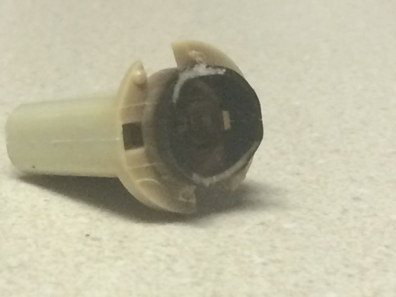 Beige and black plastic automotive part on a speckled surface.