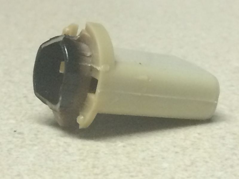 Damaged beige plastic automotive clip with dark insert