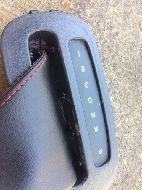 2002 Pontiac Grand Prix - A close-up view of a black automatic gear shifter surround with red stitching on the leather boot. The gear indicator shows '1', '2', '3',…