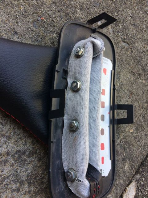 2002 Pontiac Grand Prix - A close-up view shows a black leather-covered part with red stitching, attached to a black plastic housing with metal bolts and gray fabric…