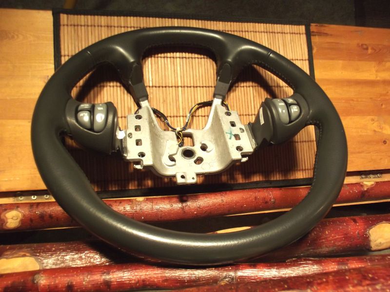Black steering wheel with cruise control buttons on metal column