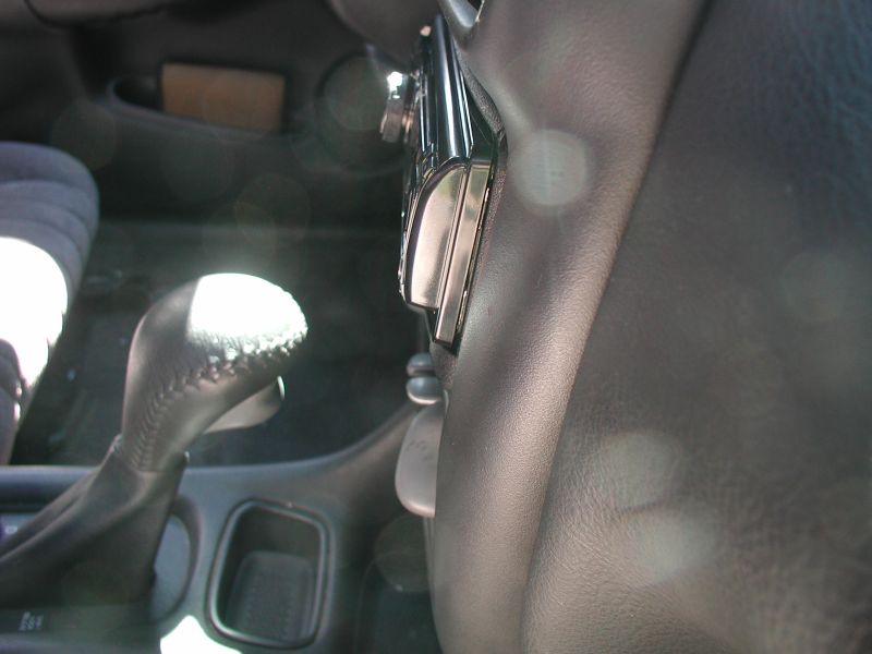 Car interior showing gear shifter and center console controls with sun flare.