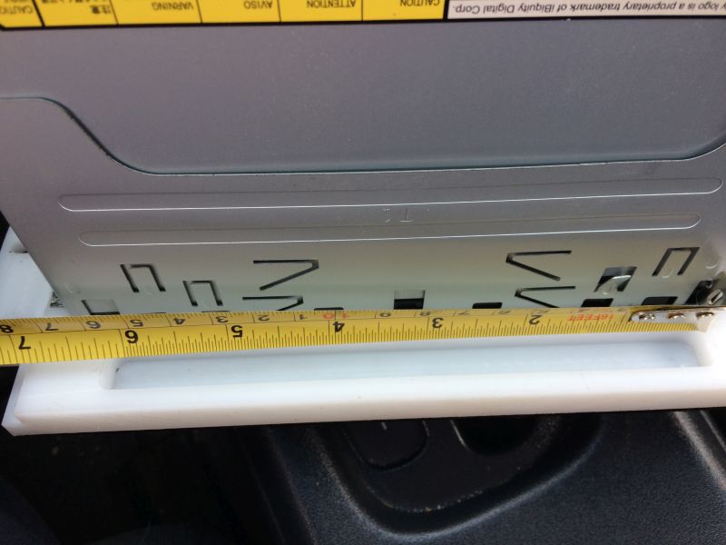 Yellow measuring tape across front of silver car stereo unit, showing 4 inch measurement.