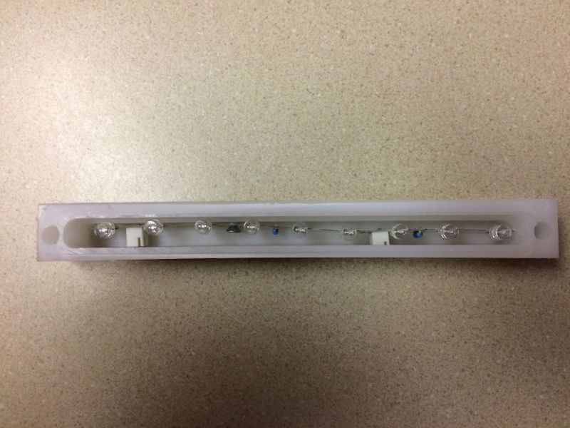 White plastic housing with a strip of small light bulbs and blue components.