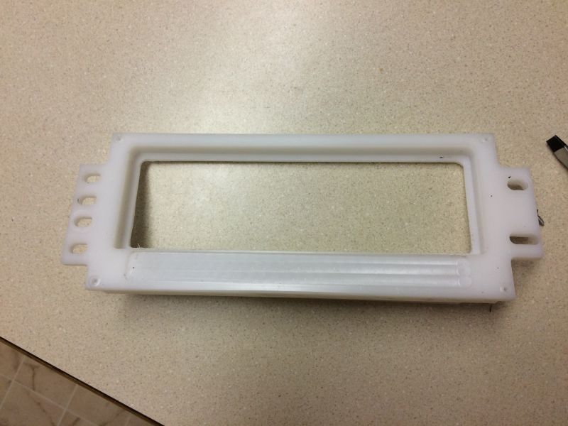 White plastic rectangular frame with a central opening and holes on the sides.
