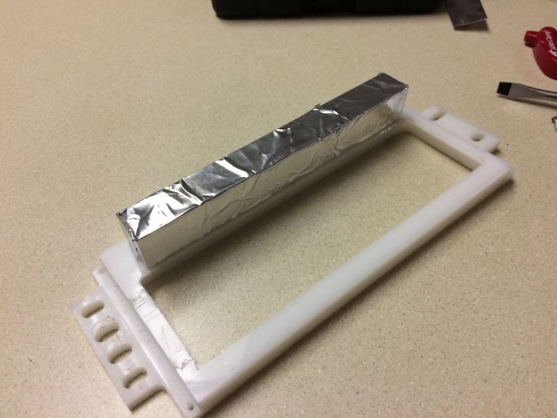 Object wrapped in foil on a white plastic frame