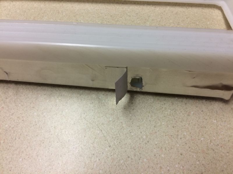 Gray paper taped to white plastic with a blue hole underneath.