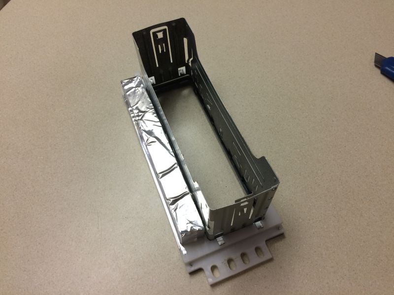 Metal bracket with foil insulation on a countertop next to a utility knife.