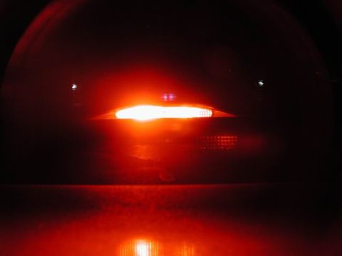 2002 Pontiac Grand Prix - A close-up, low-angle shot of a bright red taillight assembly on a dark vehicle, reflecting onto a wet surface below.