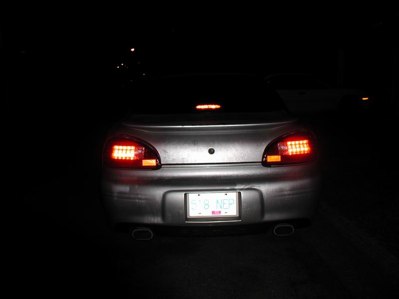 Rear view of a silver 2002 Pontiac Grand Prix with illuminated brake lights and license plate.