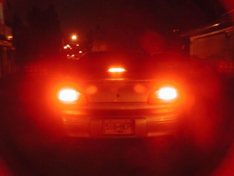 2002 Pontiac Grand Prix - The rear of a silver Pontiac Grand Prix is illuminated by its bright red taillights at night. The license plate reads "518-NEP".