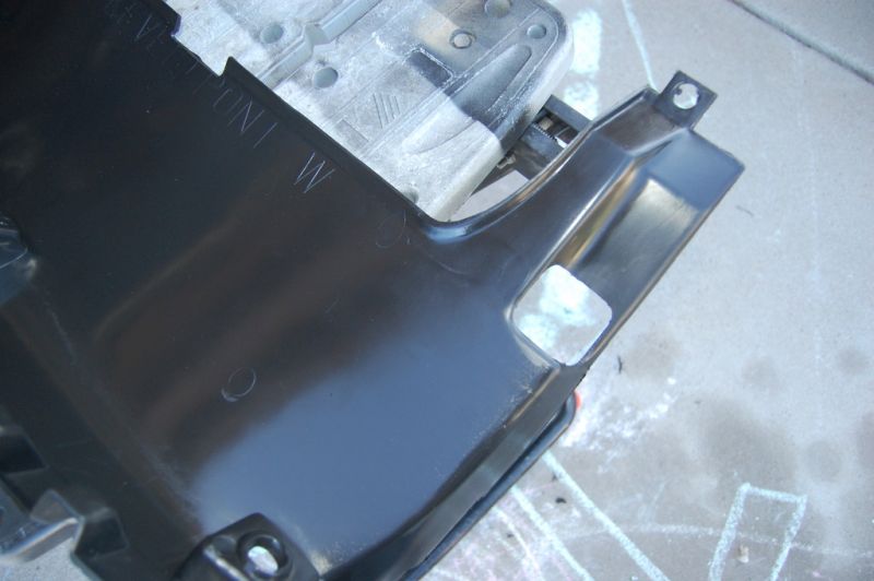 Black plastic car part with embossed text "VE FRONT W" and cut-out sections.