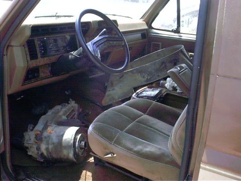 1985 Ford Bronco - The interior of a truck shows a removed transmission and parts of the dashboard are disassembled.