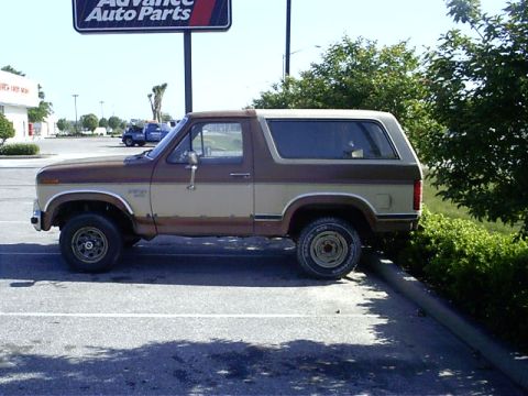 1985 Ford Bronco - Side view of a two-tone brown and tan 1985 Ford Bronco parked in a lot.