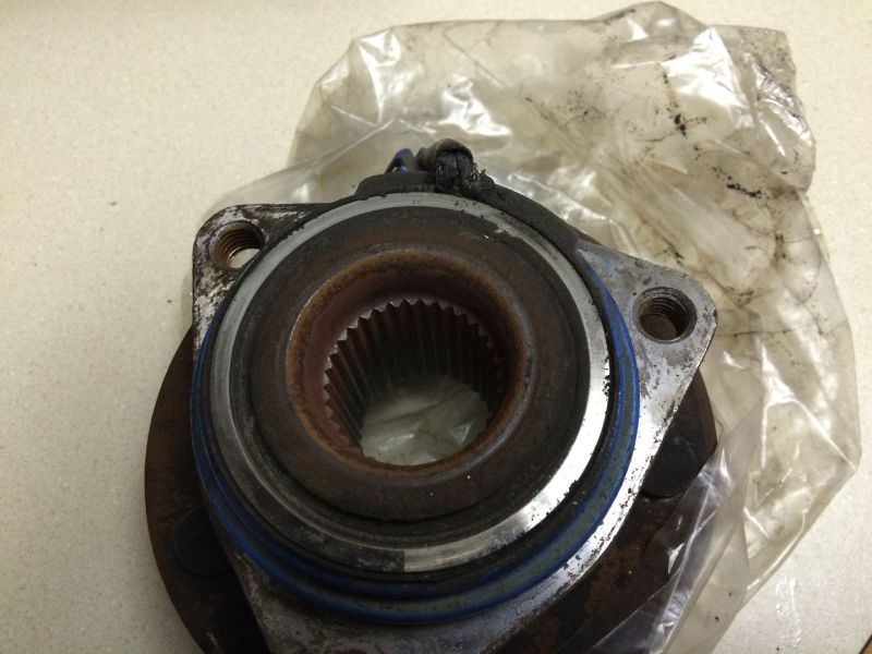 Close-up of a rusty wheel hub assembly with a blue seal.