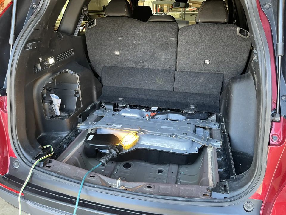 Red SUV cargo area with battery pack exposed and a yellow work light plugged in.