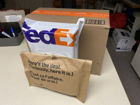 2026 Honda CR-V - A brown cardboard box with Amazon tape is behind a white FedEx package. In front of the FedEx package is a smaller brown paper package with…