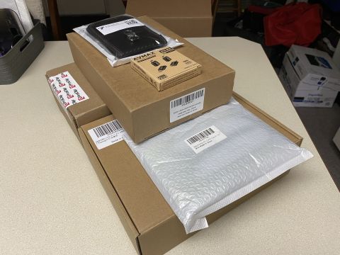 2026 Honda CR-V - Several car accessories are neatly arranged on a table. There are multiple cardboard boxes, some with shipping labels, and a black accessor…