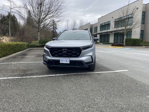 2026 Honda CR-V - A silver Honda CR-V is parked in an asphalt parking lot with a modern building in the background.