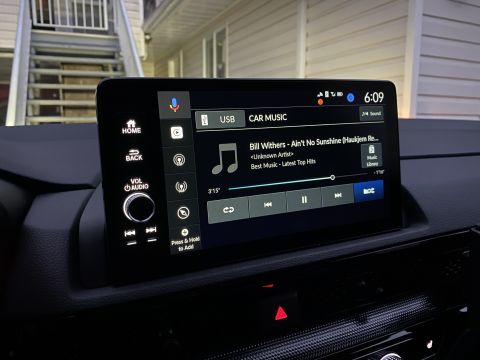 2026 Honda CR-V - A close-up interior shot of a modern car's infotainment system displaying the "CAR MUSIC" screen. The system shows song information for "Bi…