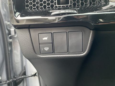 2026 Honda CR-V - A close-up view of the interior dashboard of a vehicle shows a trunk release button and a windshield wiper control button, along with two b…