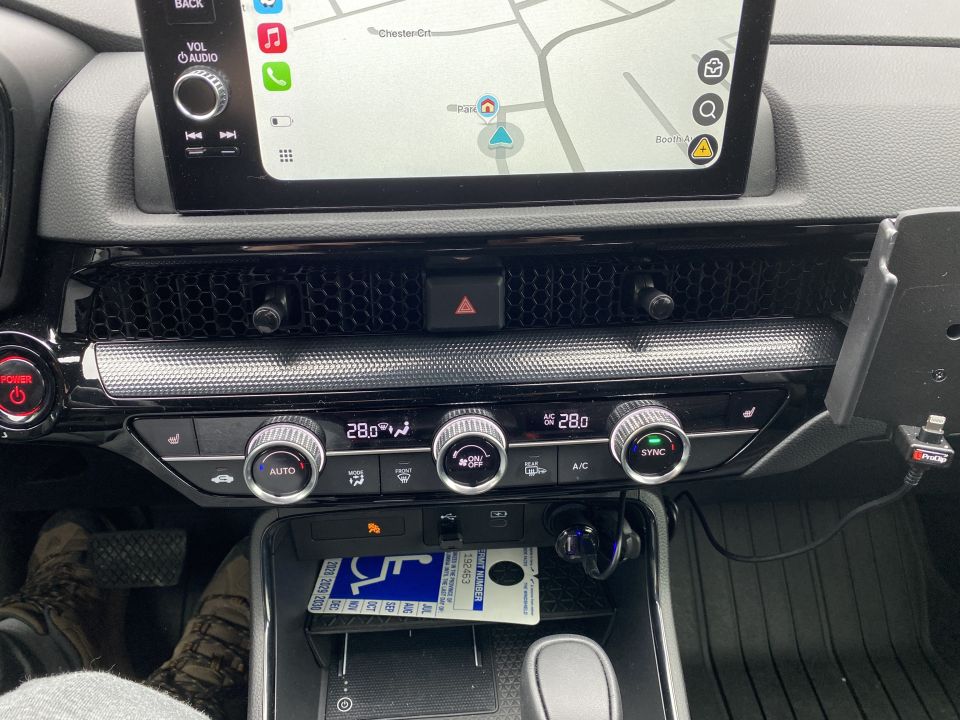 Close-up of a car's center console with touchscreen, climate controls, and a charging port.