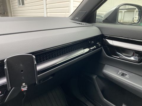 2026 Honda CR-V - Interior view of a modern car's dashboard, featuring a phone mount with a charging cable and a sleek, textured trim piece above the air ven…