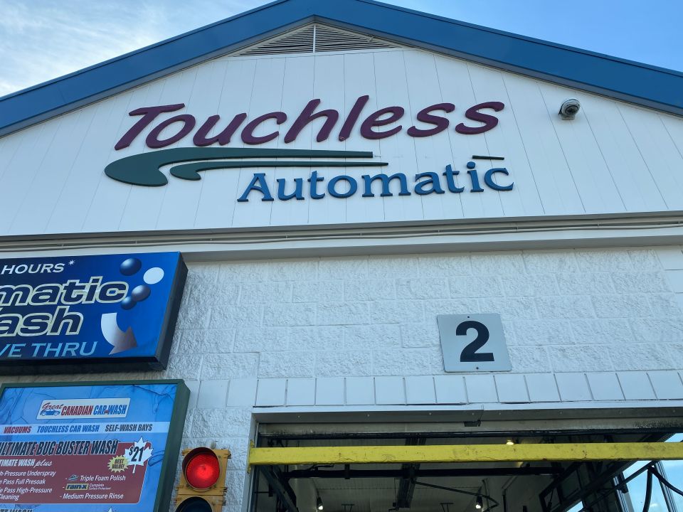 Signage for a car wash with "Touchless Automatic" and a menu of services.