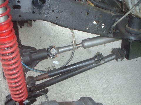 1995 Ford Bronco - Close-up view of the front suspension and steering linkage, including a red coilover shock absorber.